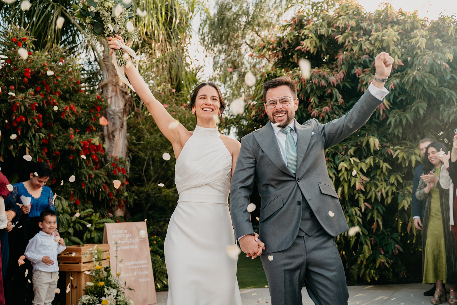 Novia alzando el ramo rodeada de invitados