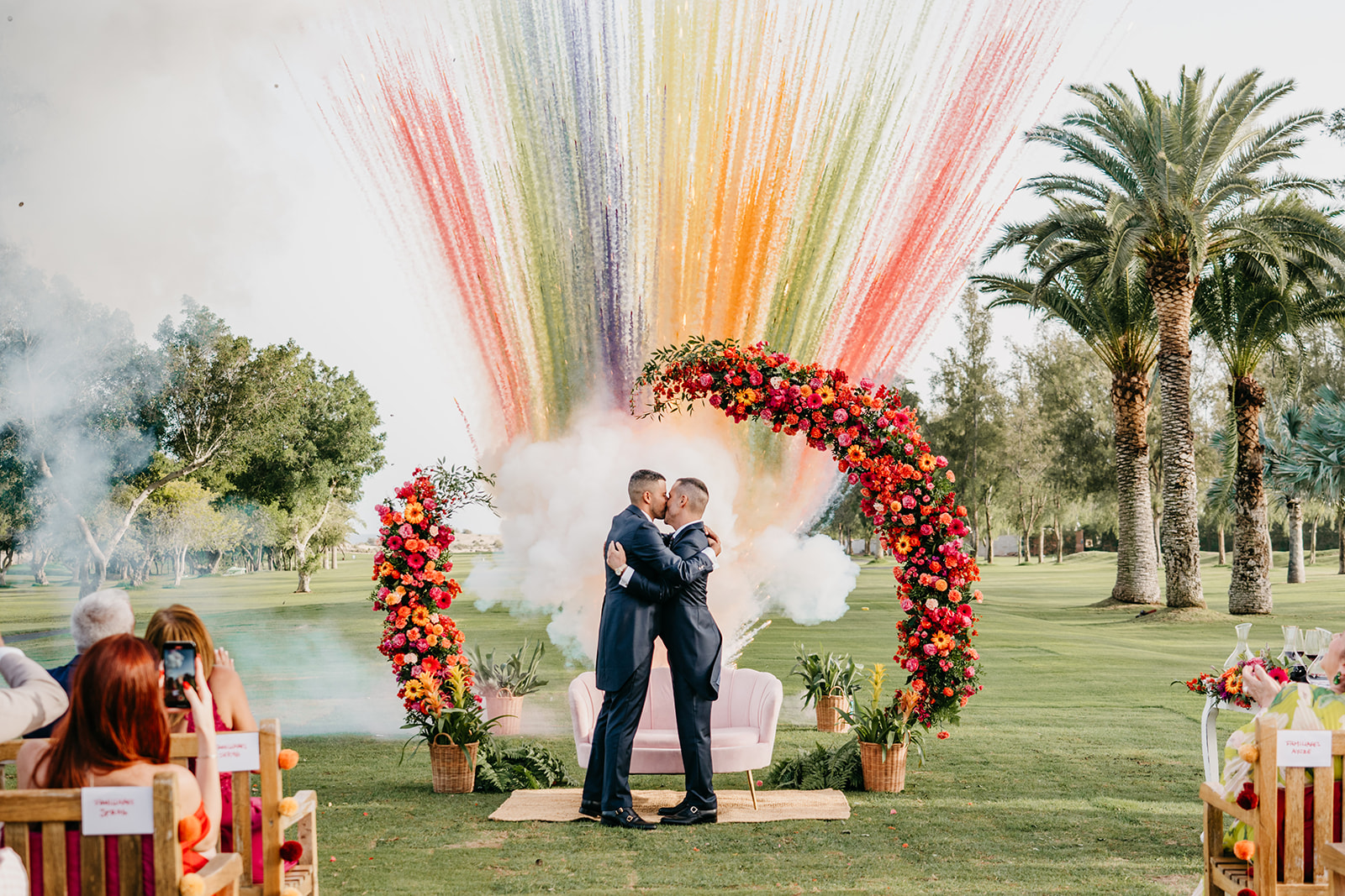 Novios junto a un arco floral lleno de color